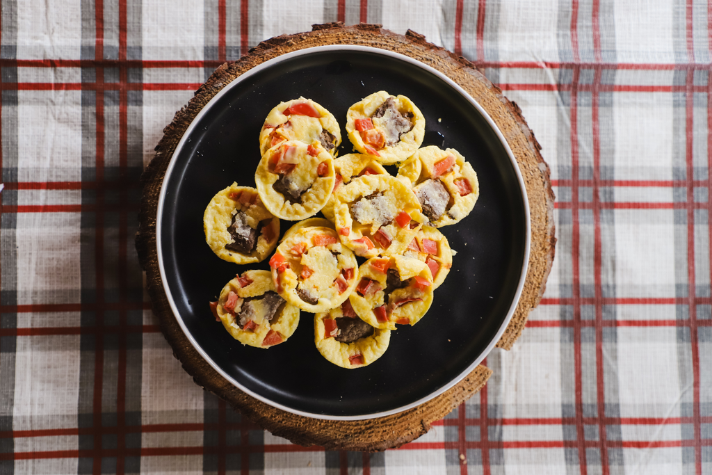 mini quiche sur un plateau noir avec un fond carreauté 